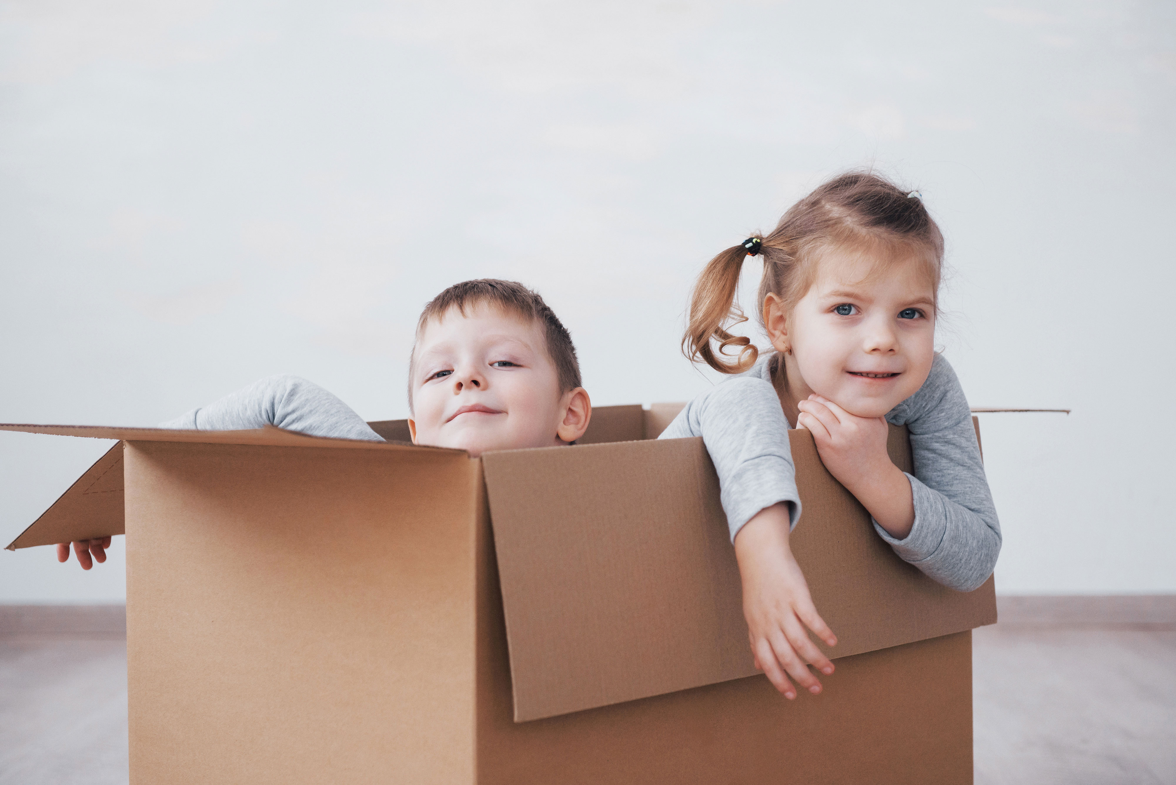 Девочка с картонной коробкой. Фото ребенок счастливый с коробкой. Пакет и ребенок стоковые фото. За бумажными малышами девочка.